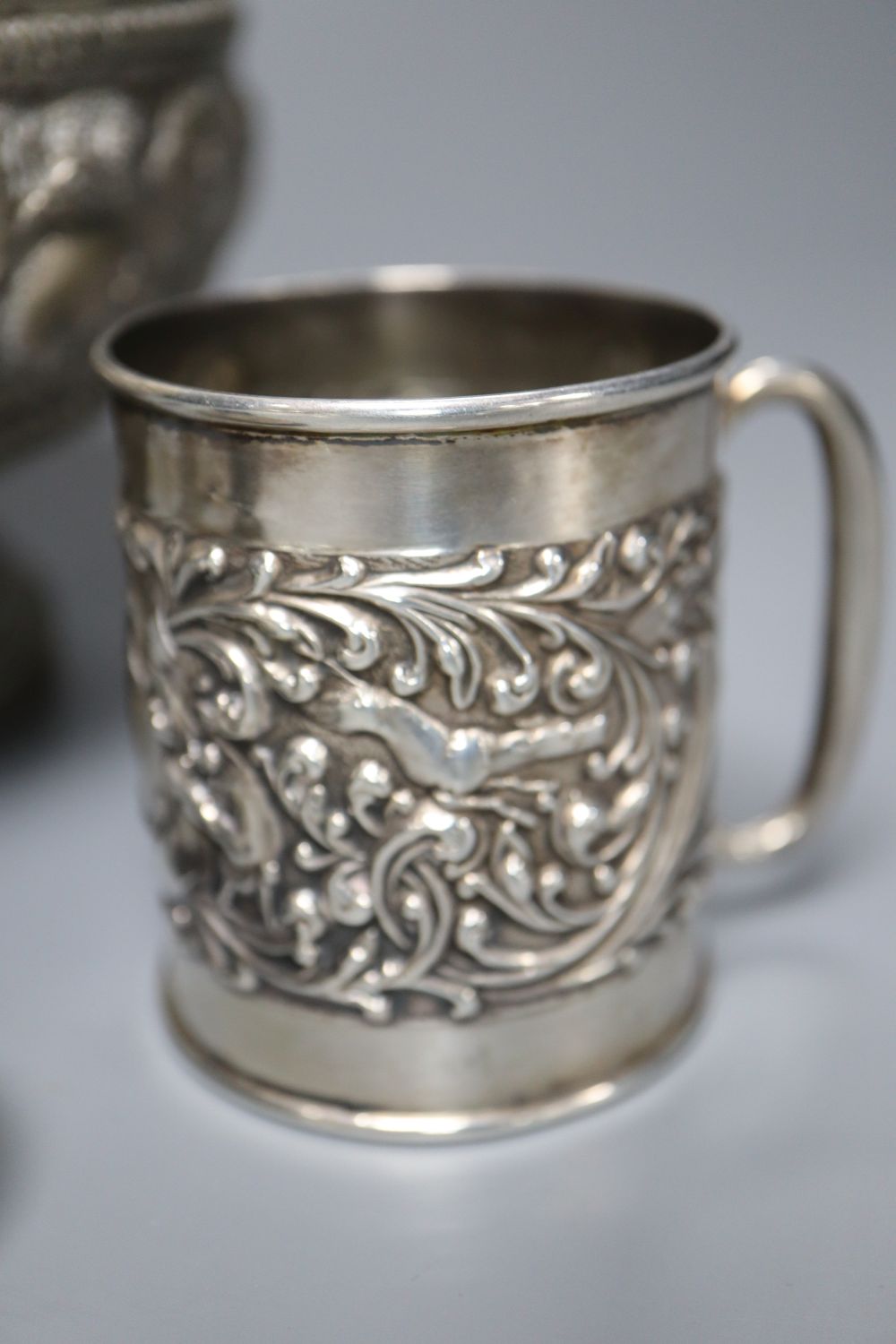 An Edwardian silver christening mug, a Victorian silver foliate sifter spoon, Indian? bowl, Chinese napkin ring & a snuff box.